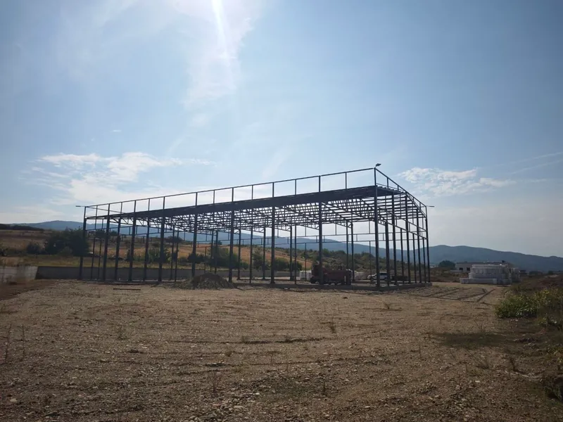 Čelična konstrukcija hale sa bočne strane, u pozadini brda